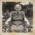 Vintage black and white photo of an elderly woman sitting outdoors.